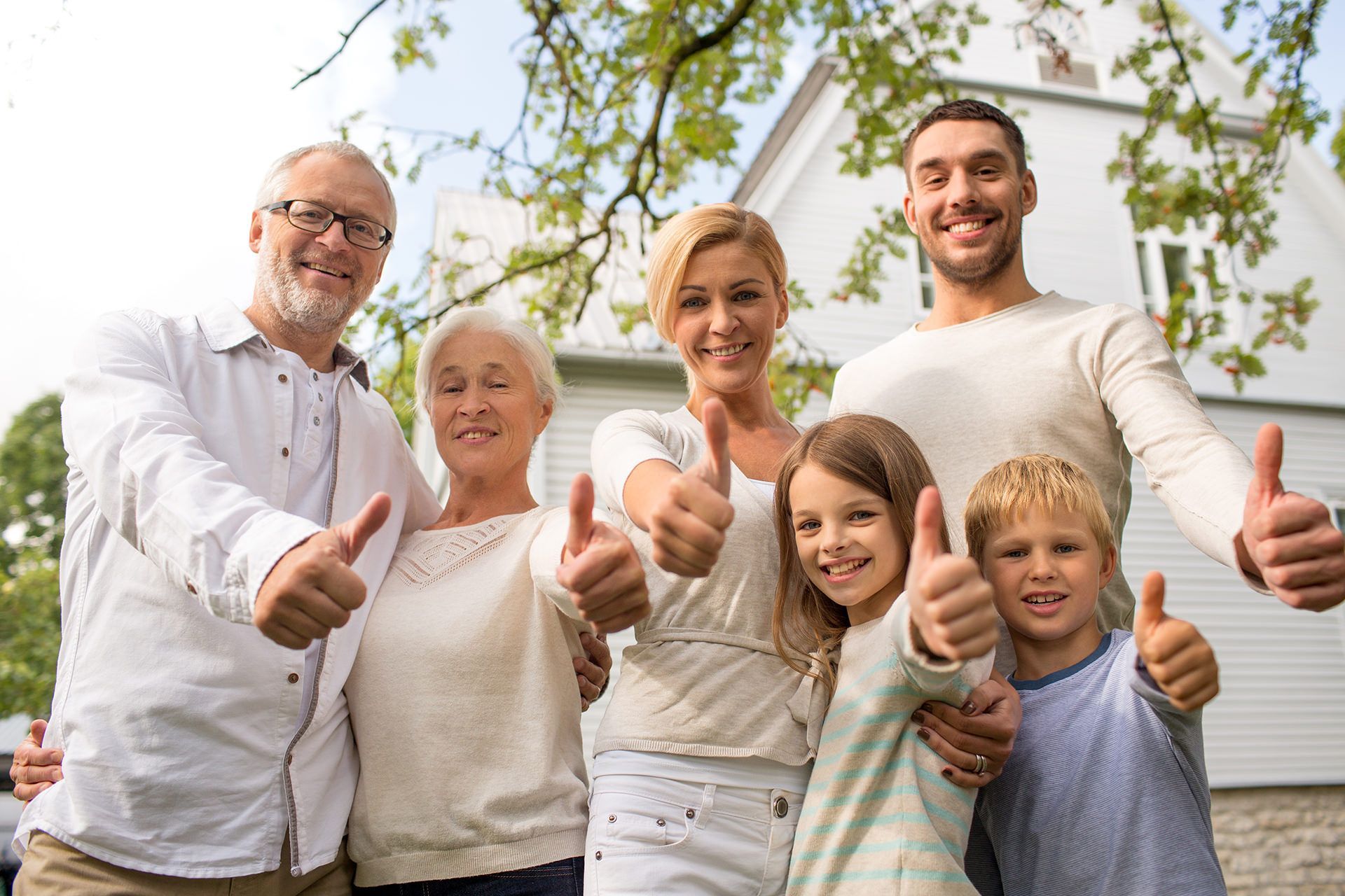a family is giving a thumbs up in front of a house .