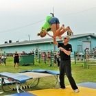 Person on a trampoline catches another person in a colorful stunt at an outdoor park.