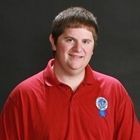 Person in a red polo shirt smiling against a dark studio background.