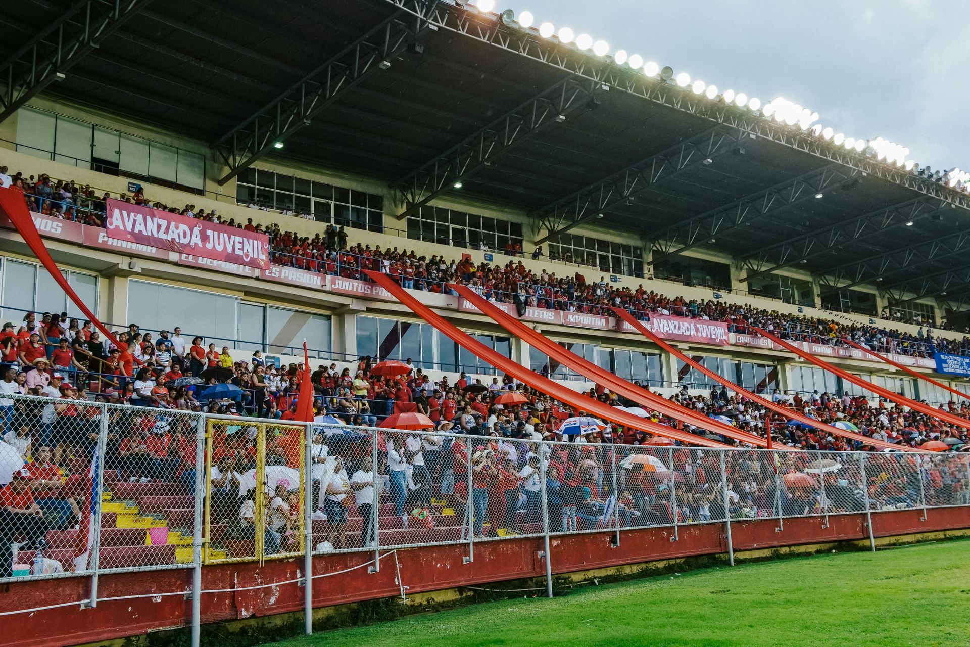 Crowded soccer stadium with red banners and fans in the stands behind a goal