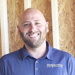 Bald man with beard smiles in a blue shirt, 
