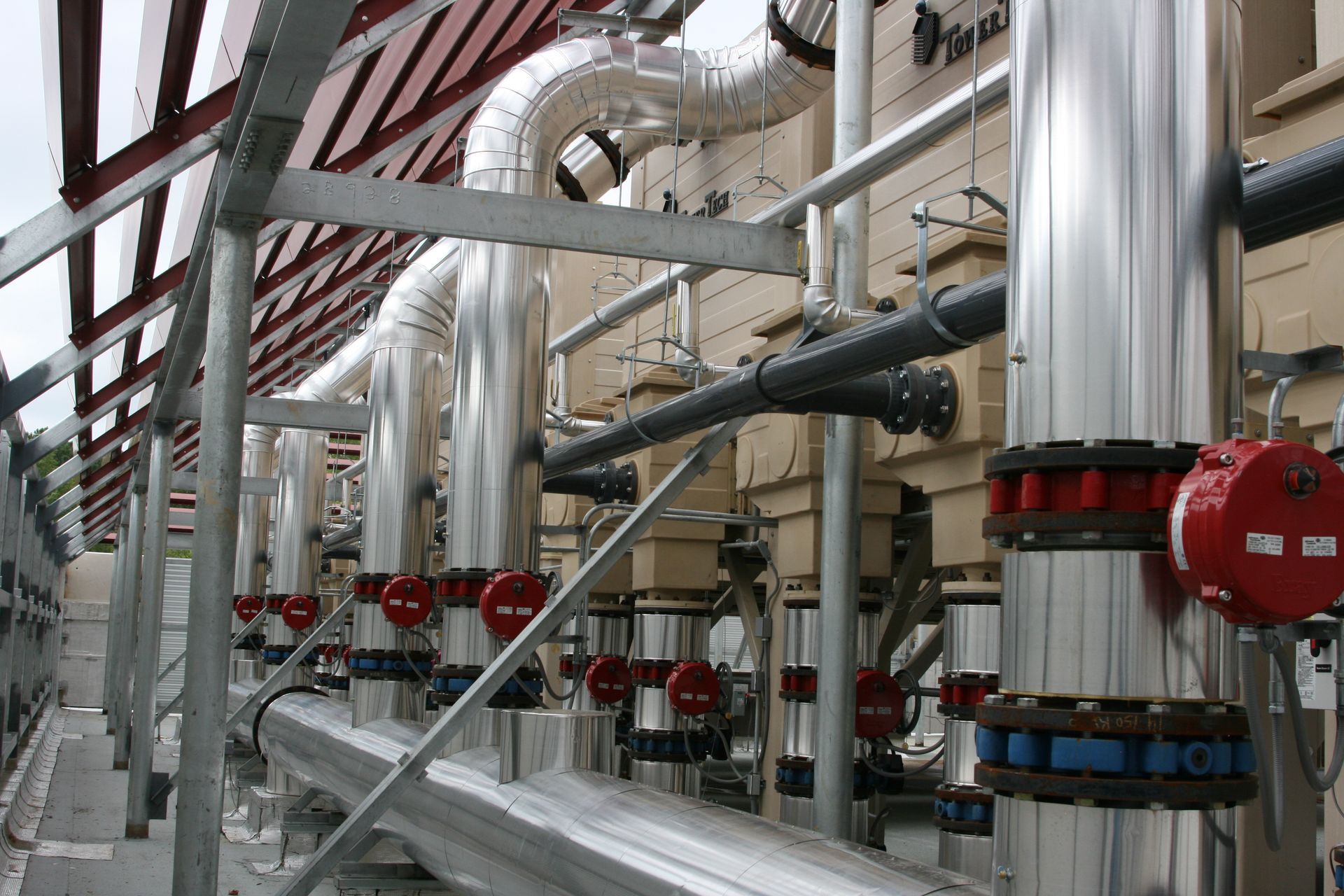 Industrial pipes and valves in a stainless steel processing facility with red and black fittings