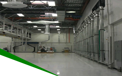 Large industrial warehouse interior with polished floor, overhead pipes, and storage tanks along the right wall