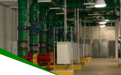 Industrial room with green pipes, red pumps, and white equipment in a clean utility facility