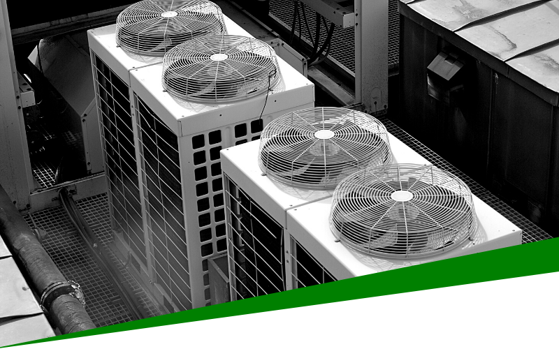Three rooftop HVAC units with large fans on a commercial building, seen in black and white.