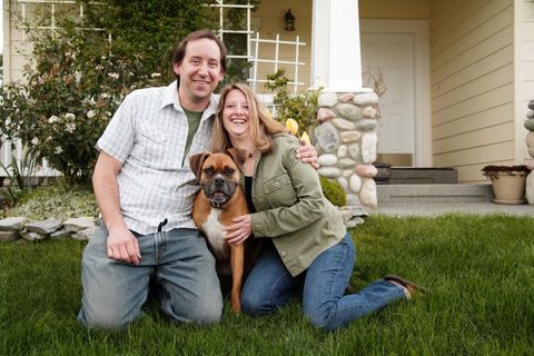 Happy couple in front of house with dog
