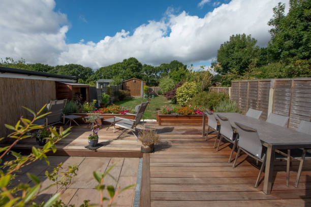 A wooden deck with a table and chairs in a garden.
