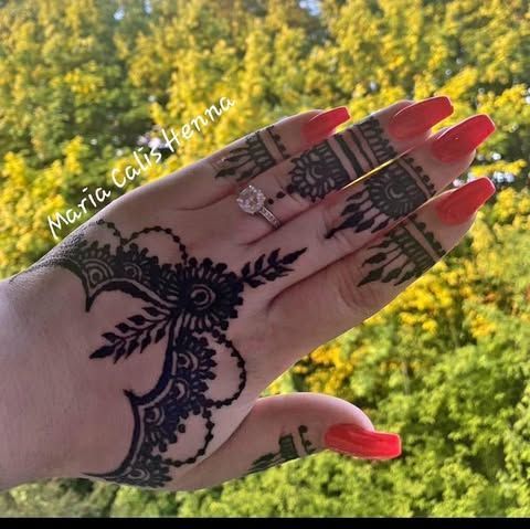 La main d'une femme avec un tatouage au henné et des ongles rouges