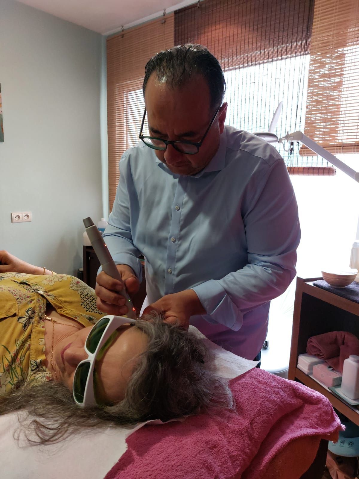 Un homme donne à une femme un traitement au laser sur son visage.