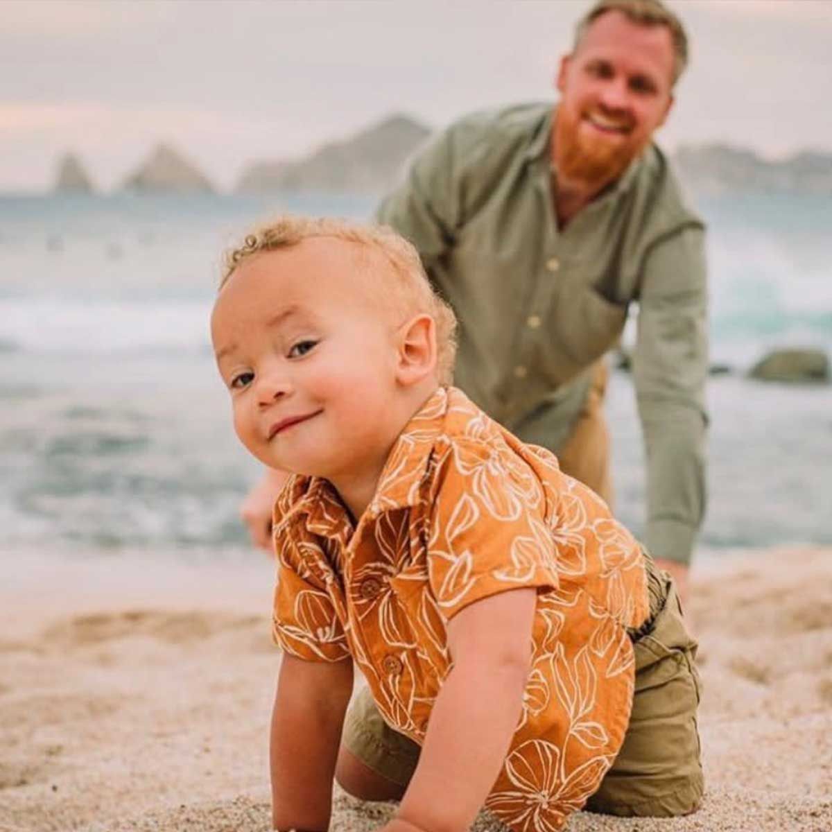 Life after a hiring a private chef, a little boy is crawling on the beach next to a man