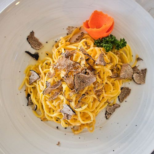A white plate topped with noodles and truffle on a table.