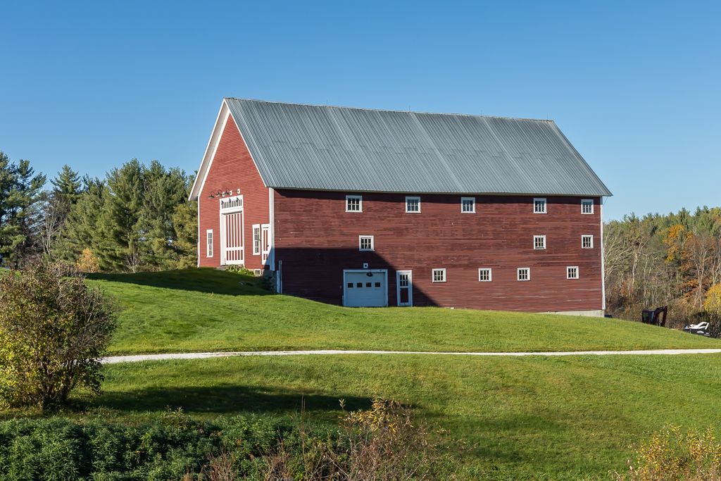 A large red barn sits on top of a grassy hill
