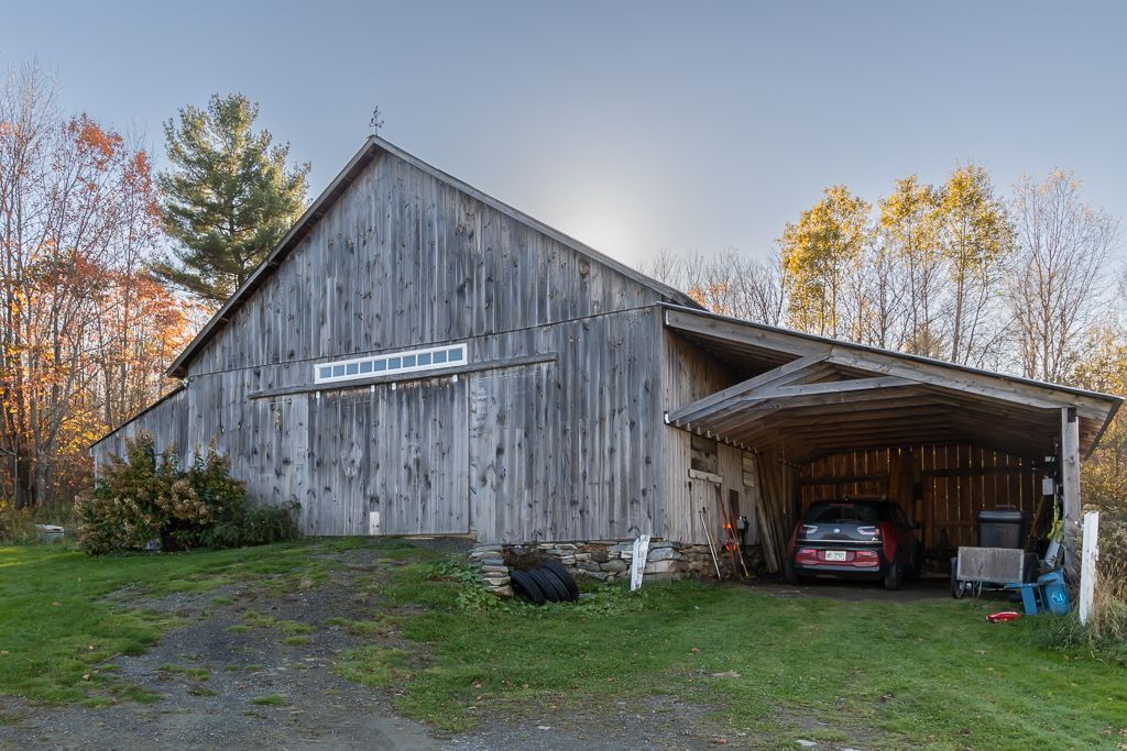 A car is parked in front of a wooden barn