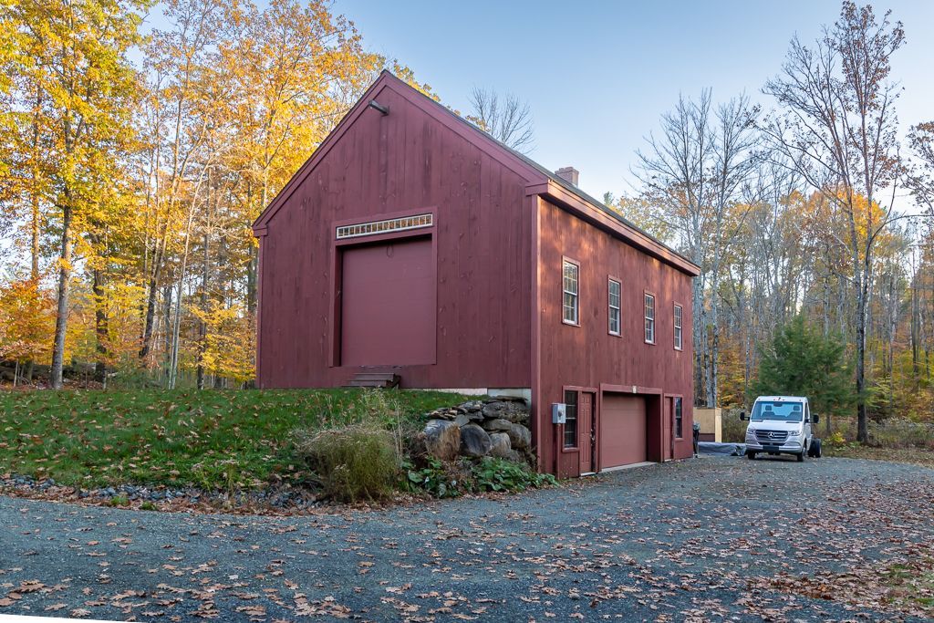 A red barn with a white van parked in front of it