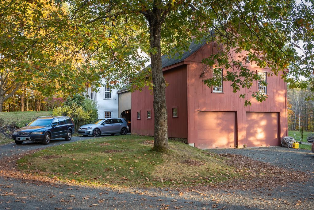 Two cars are parked in front of a red barn