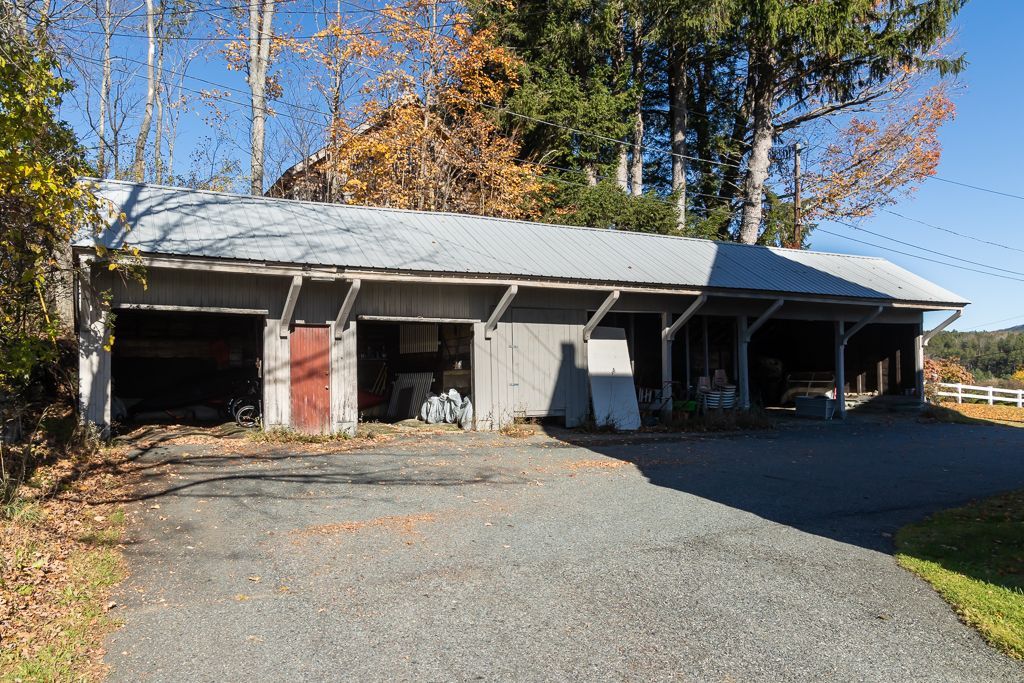 A garage with a red door is surrounded by trees
