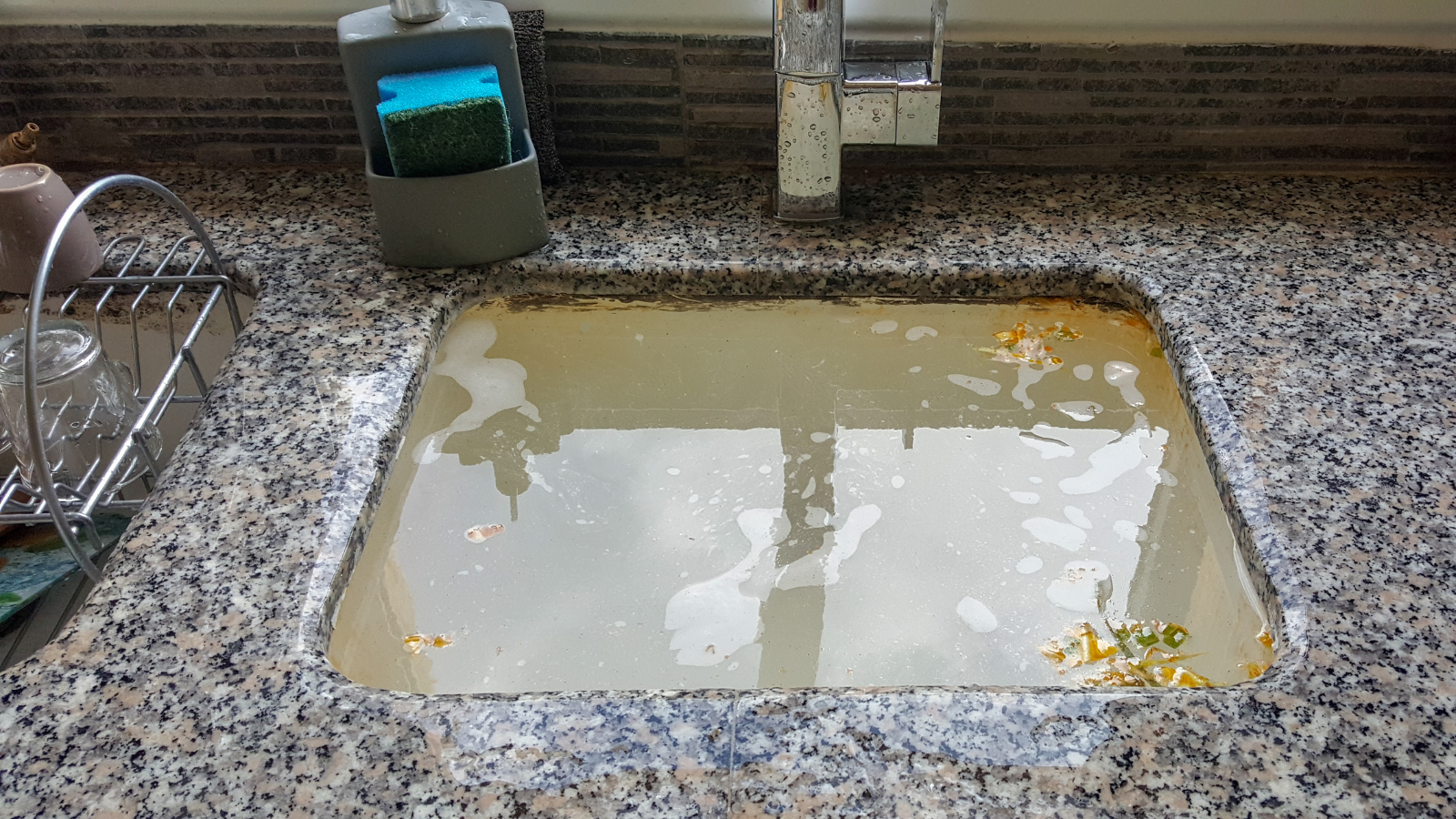 A sink is clogged with high water in a kitchen.