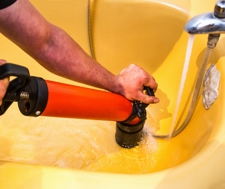 plumbing repair - drain cleaning Plumber performing drain cleaning in tub