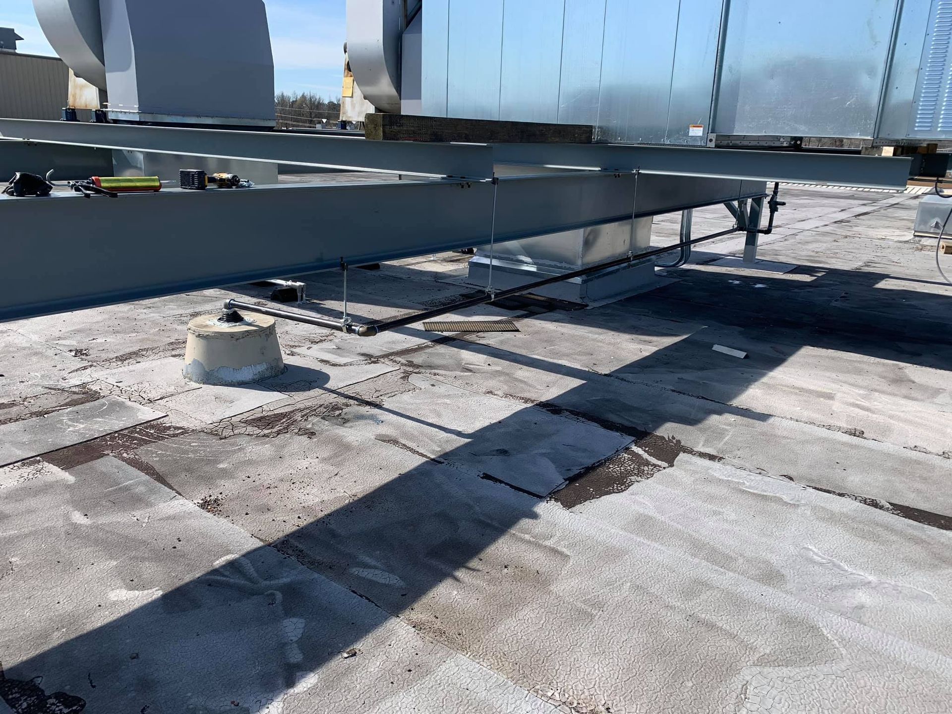 Rooftop HVAC units on a flat roof with metal ductwork and strong shadows.
