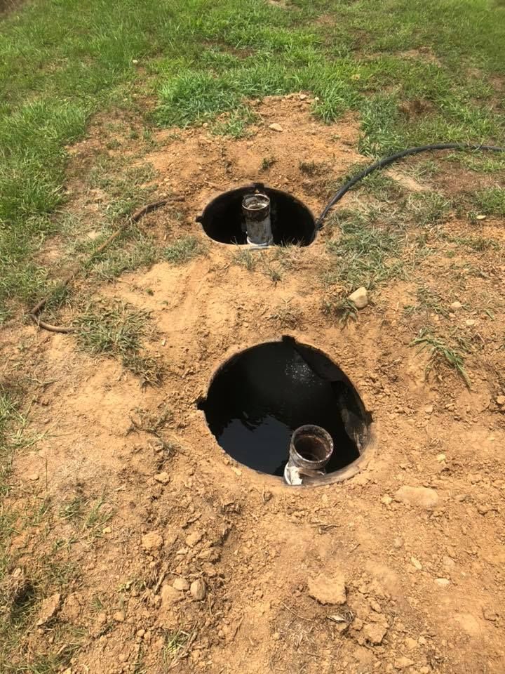 Two black utility boxes set in a grassy dirt patch with cables coming out.