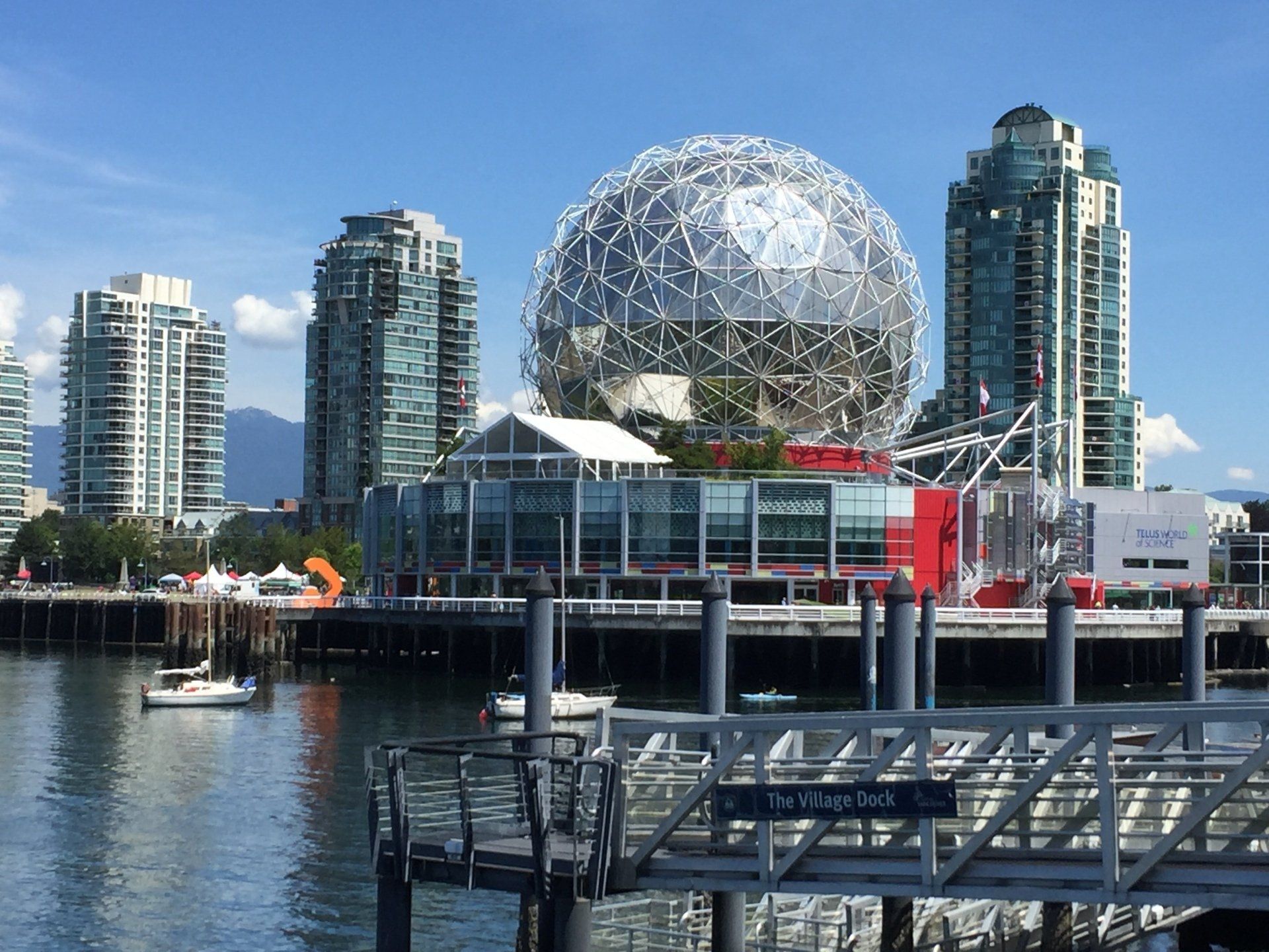 Science World building in Vancouver, BC, with geodesic dome, water, and tall buildings on a sunny day.