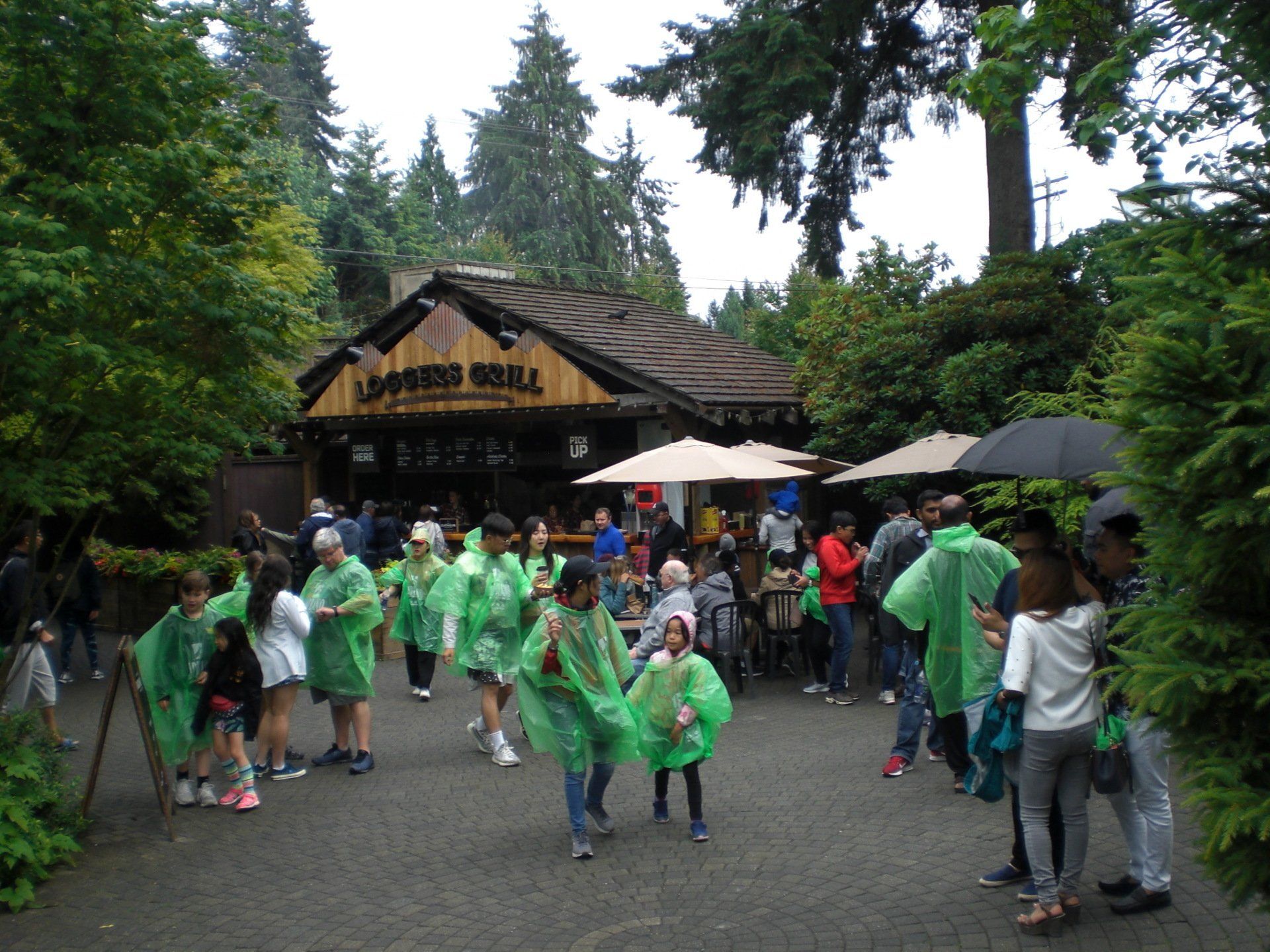 People in green ponchos near a rustic 