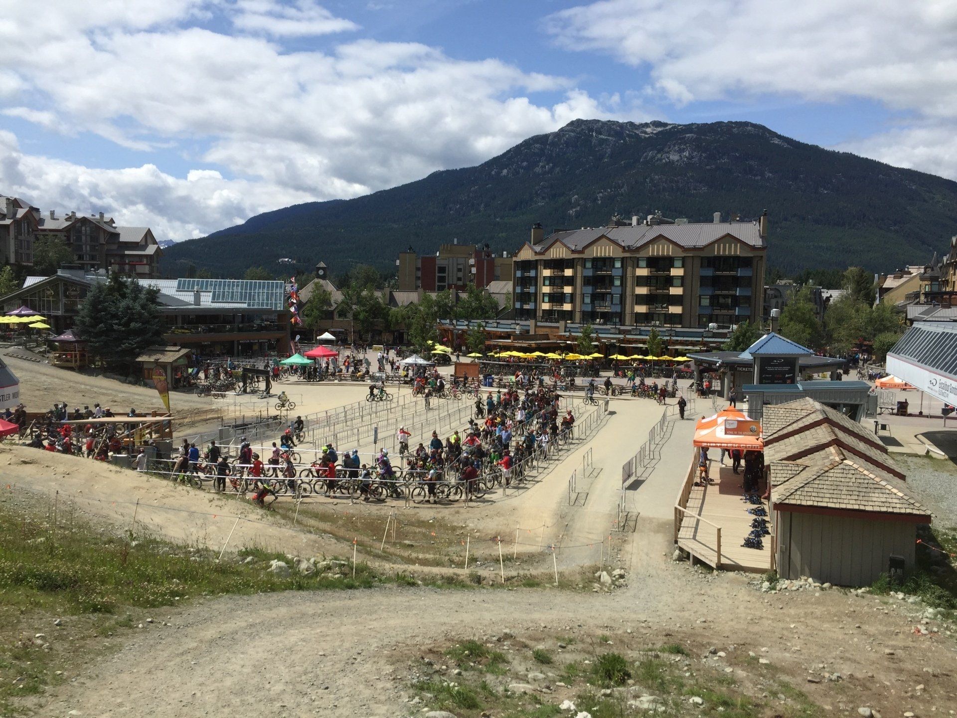 Busy outdoor scene with people and buildings, set against a mountain.