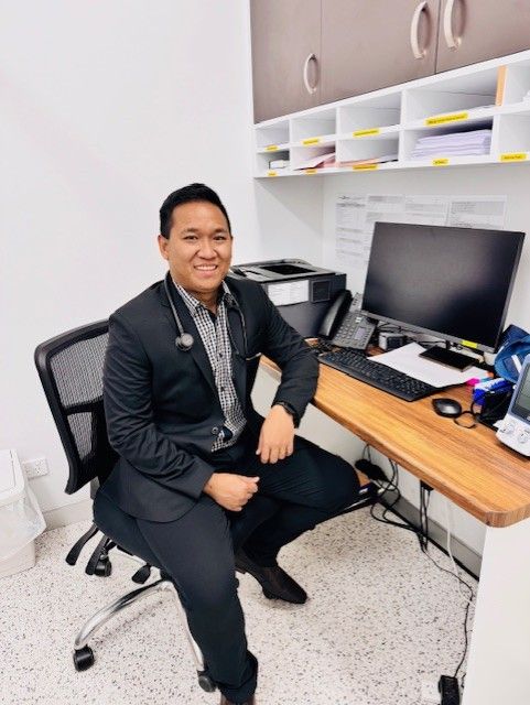A woman is sitting at a desk with a stethoscope around her neck.