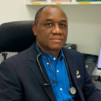 A man in a suit and blue shirt is sitting in a chair with a stethoscope around his neck.