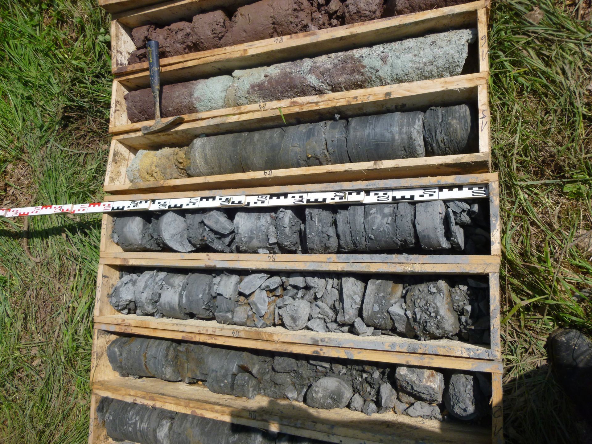 Bodenproben in Holzkisten, die Schichten unterschiedlich gefärbter Erde zeigen.