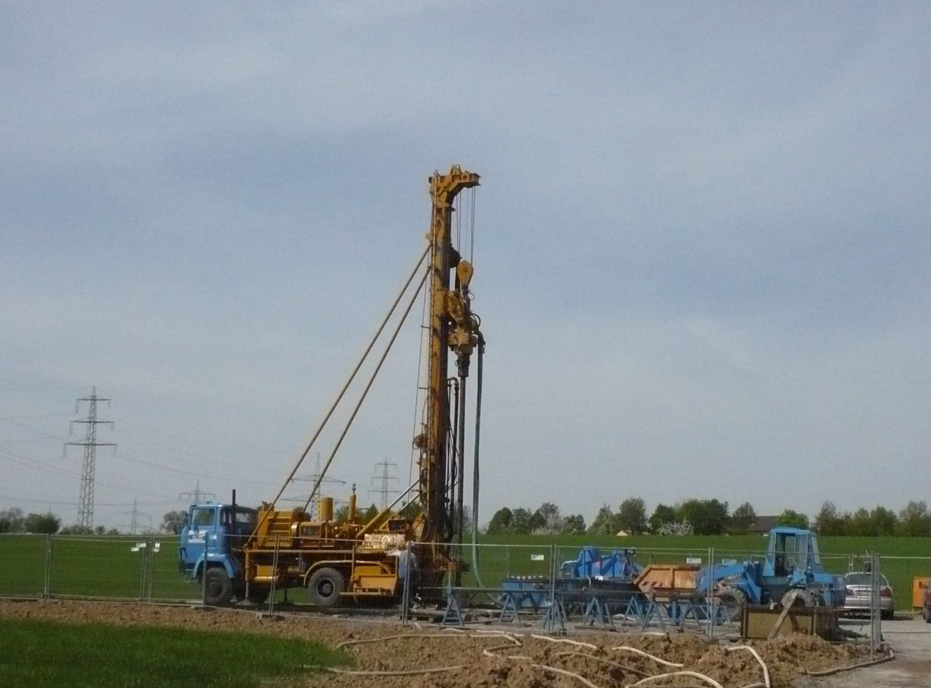 Bohranlage auf einem LKW, bereit zum Bohren im Freien, blauer und gelber, bedeckter Himmel.