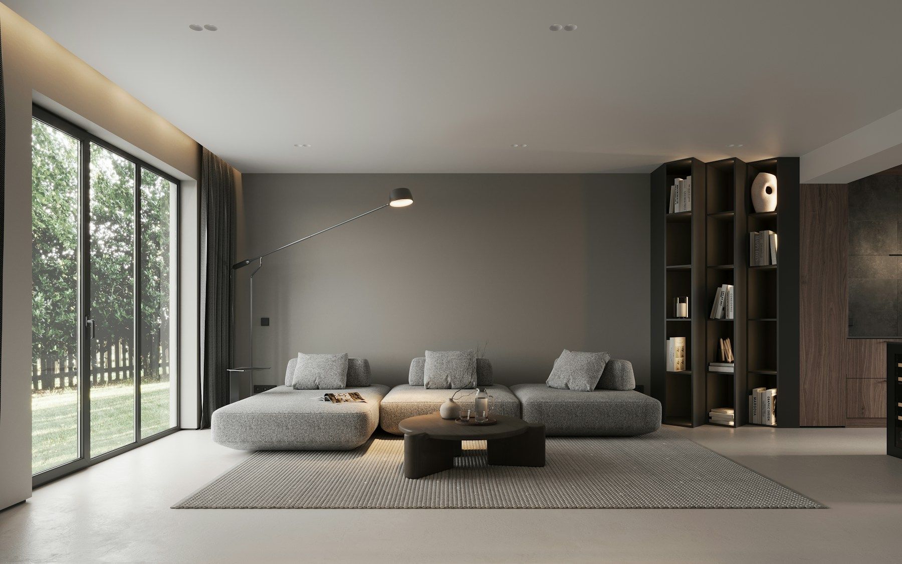 Modern living room with gray sectional sofa, coffee table, rug, and large sliding glass doors overlooking greenery