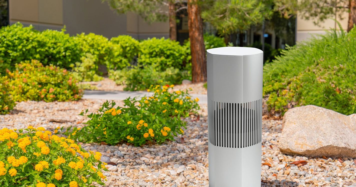 A white cylinder is sitting on top of a pile of gravel in a garden.
