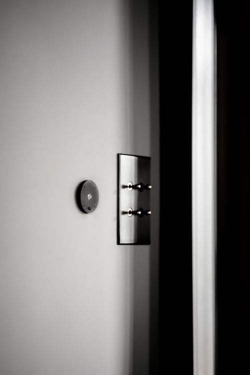 A black and white photo of a light switch on a wall.