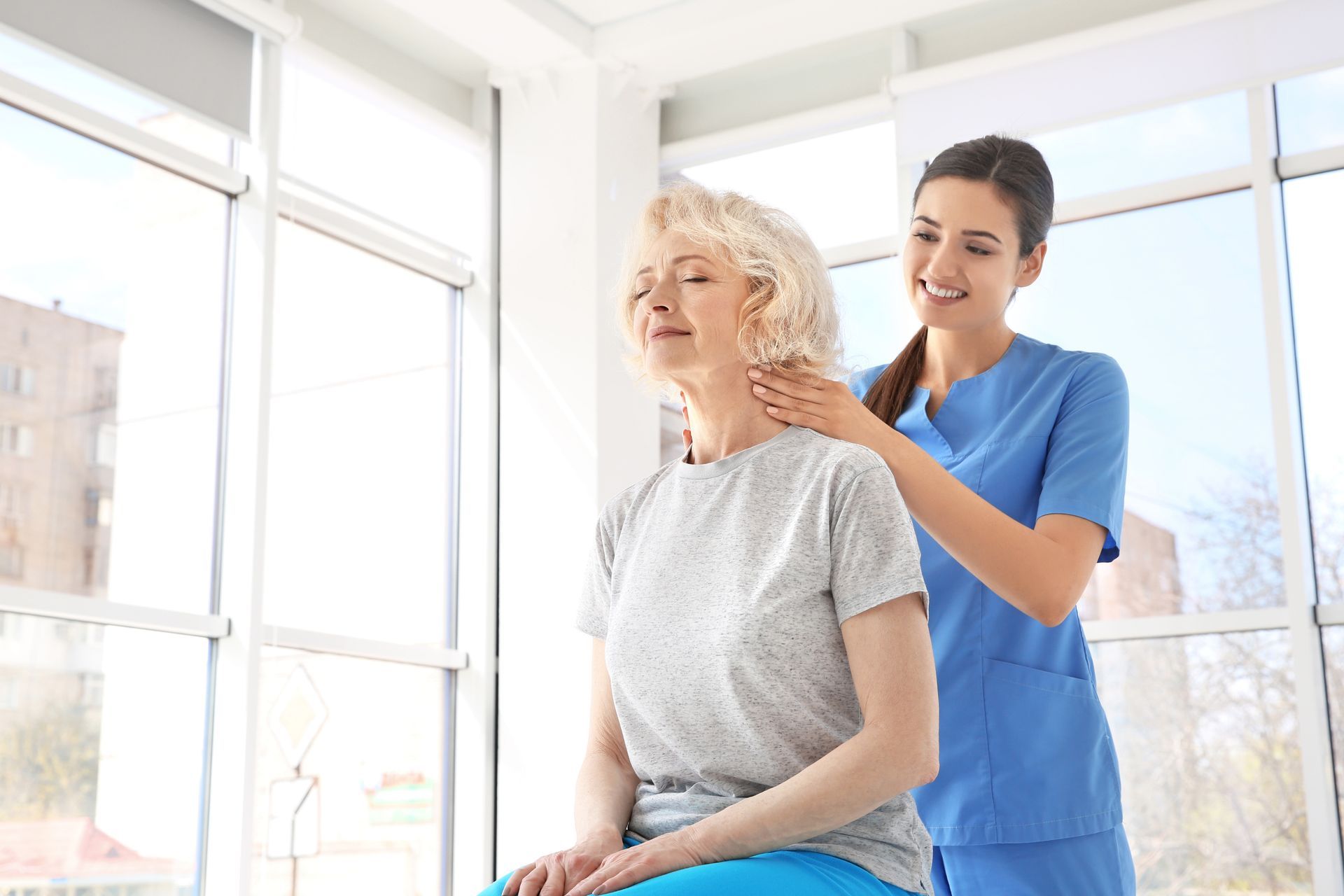 A physiotherapist is performing neck pain physiotherapy on an elderly patient in the clinic.