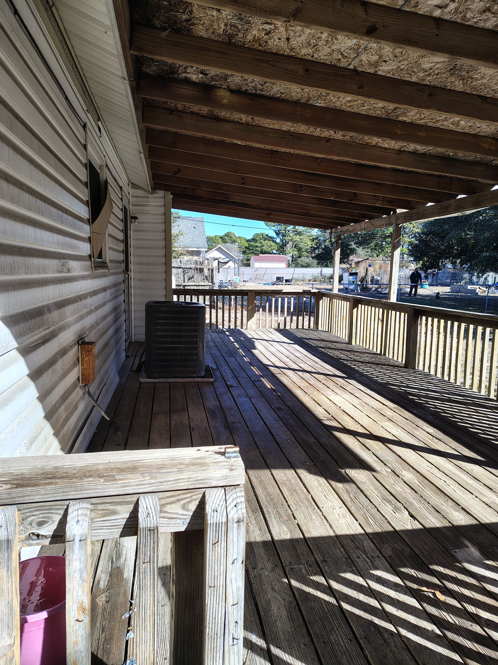 A wooden porch with a roof and a shadow of a person on it.