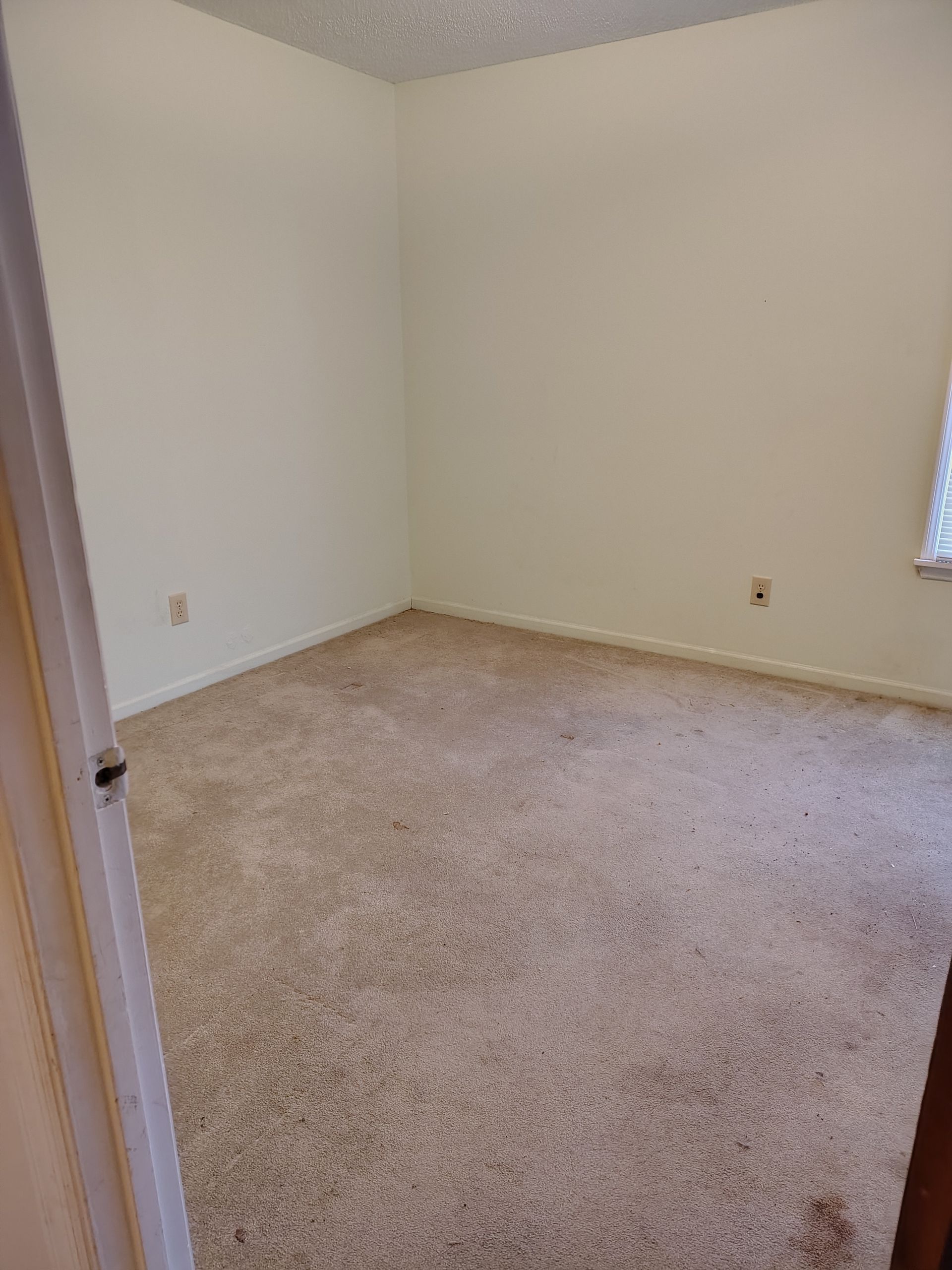 An empty bedroom with a carpeted floor and white walls.