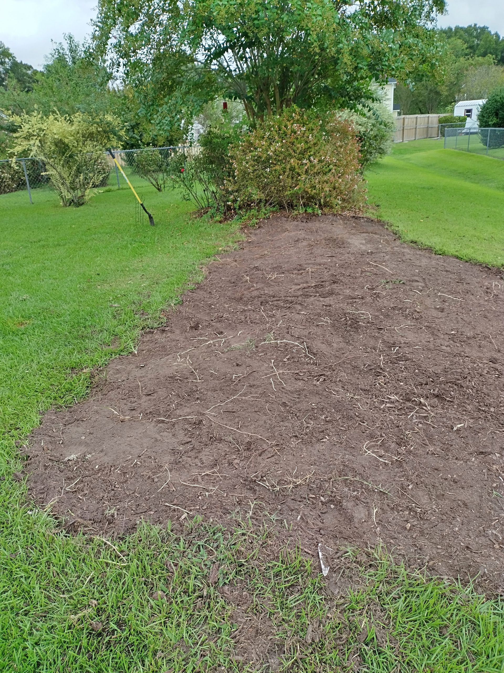 A pile of mulch is sitting in the middle of a lush green yard.