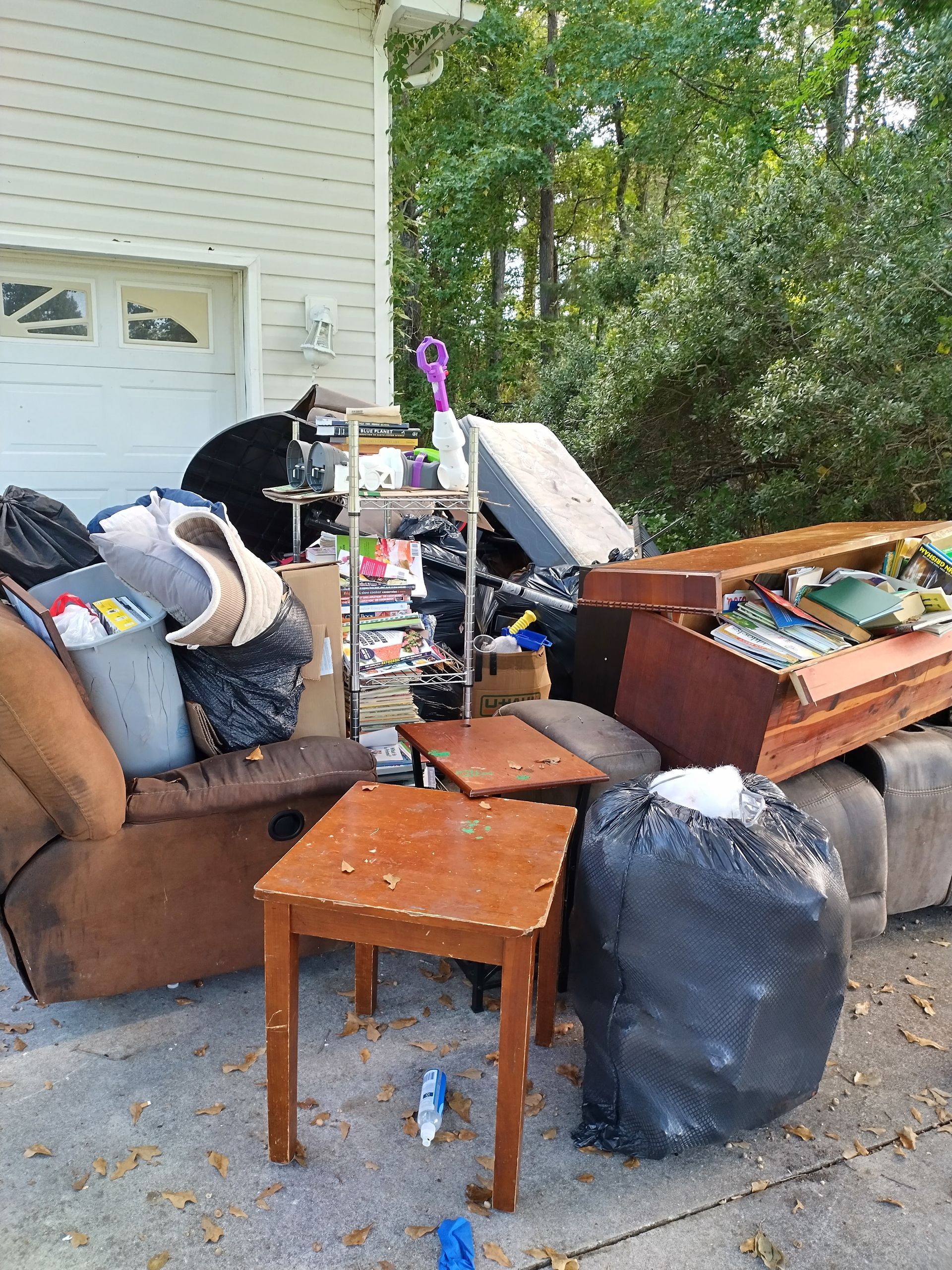 A pile of junk is sitting on the sidewalk in front of a house.