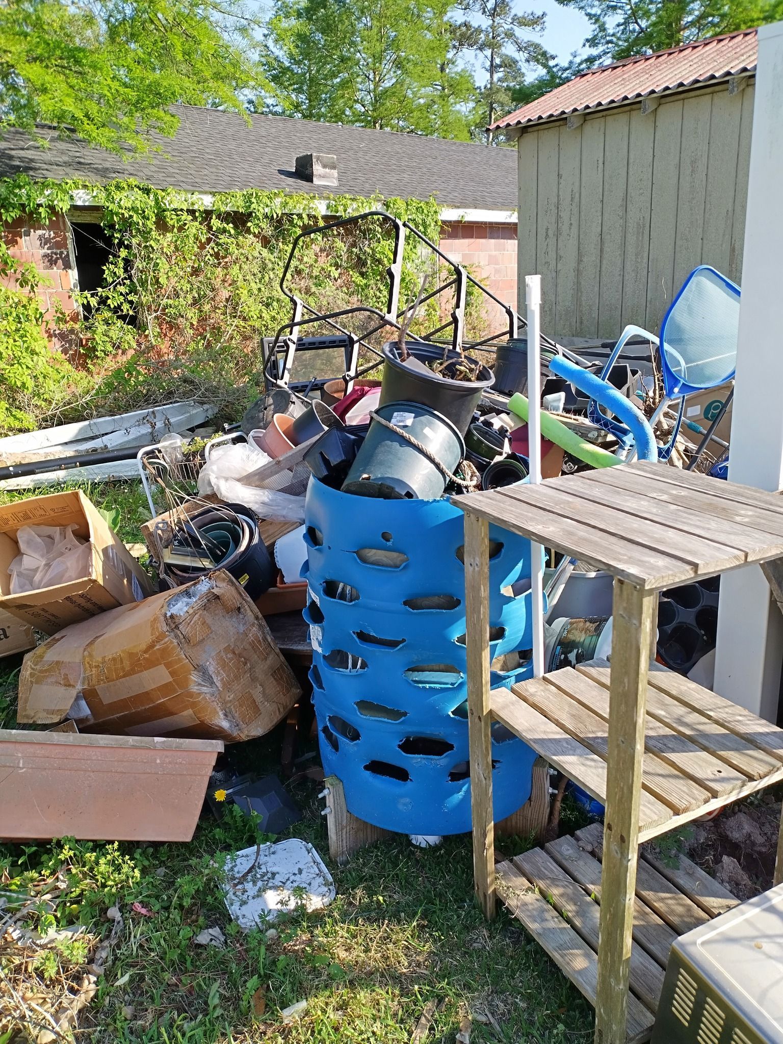 A pile of trash is sitting in the grass in front of a shed.