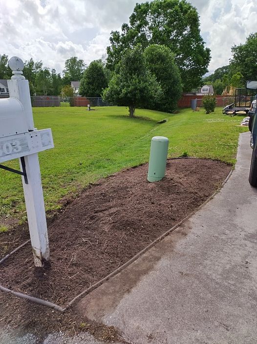 A white mailbox is sitting on the side of a driveway next to a grassy field.