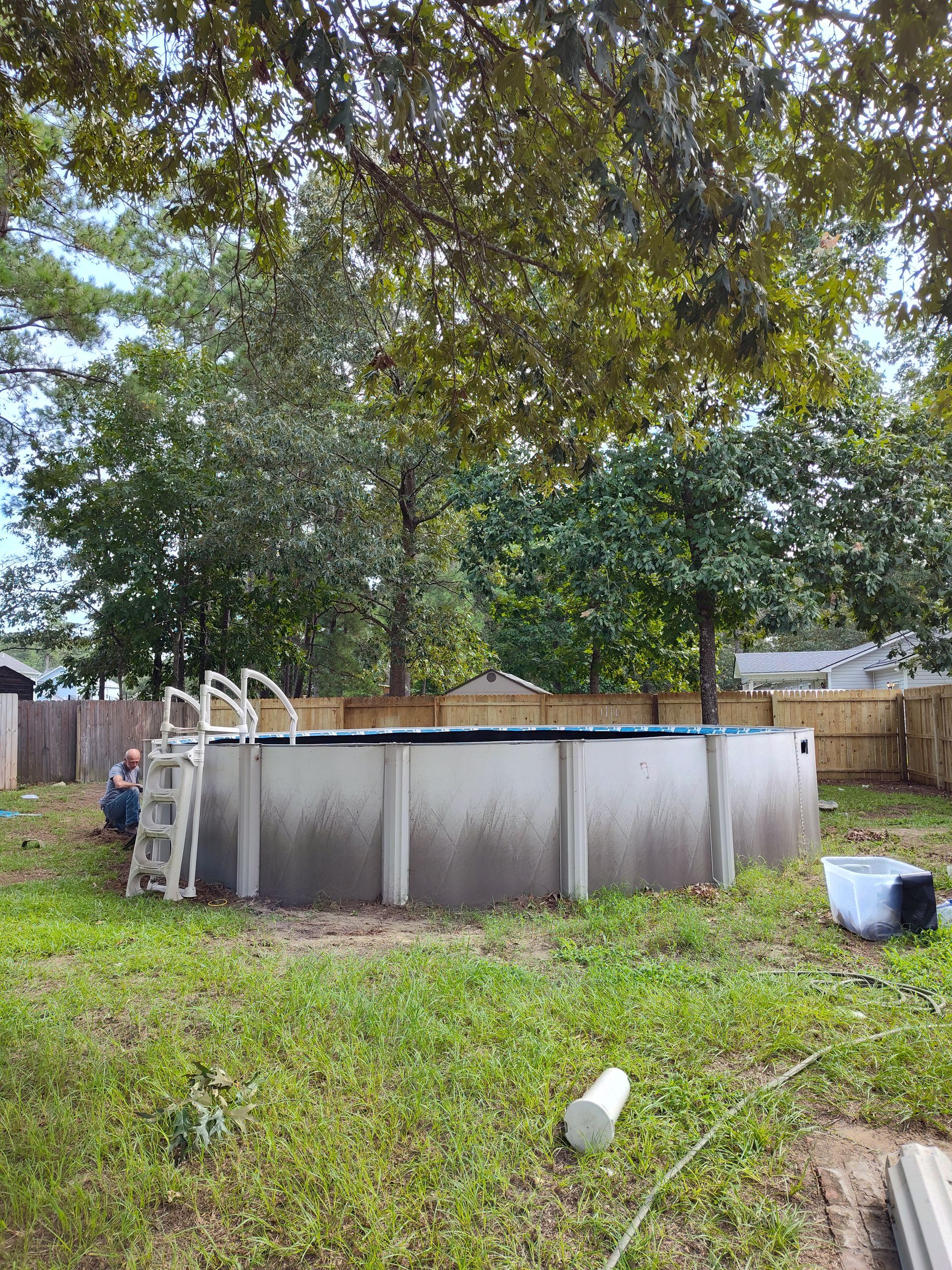 A large swimming pool is sitting in the middle of a lush green yard.