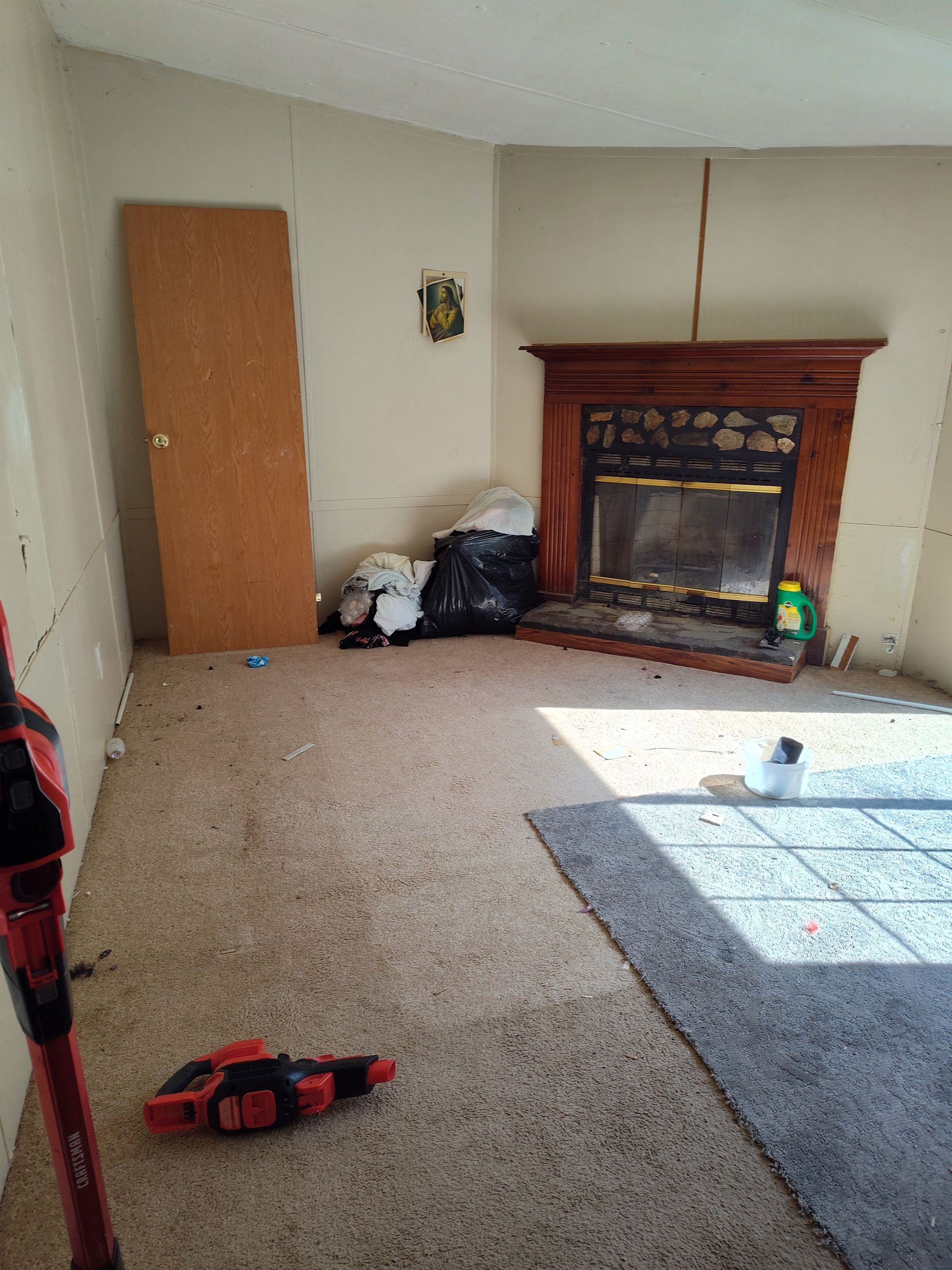 An empty living room with a fireplace and a door.