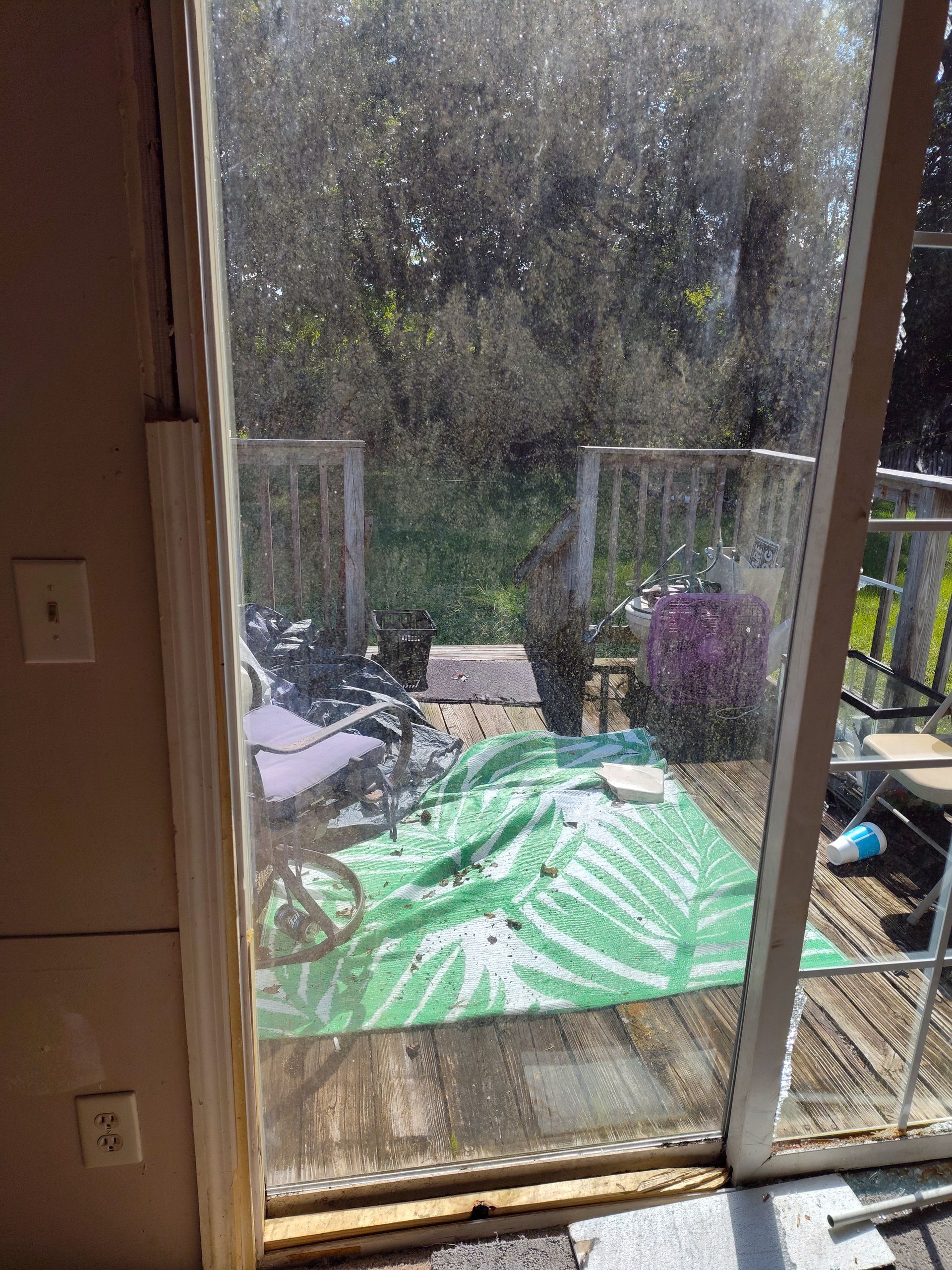 A sliding glass door with a green tarp on the floor in front of it.