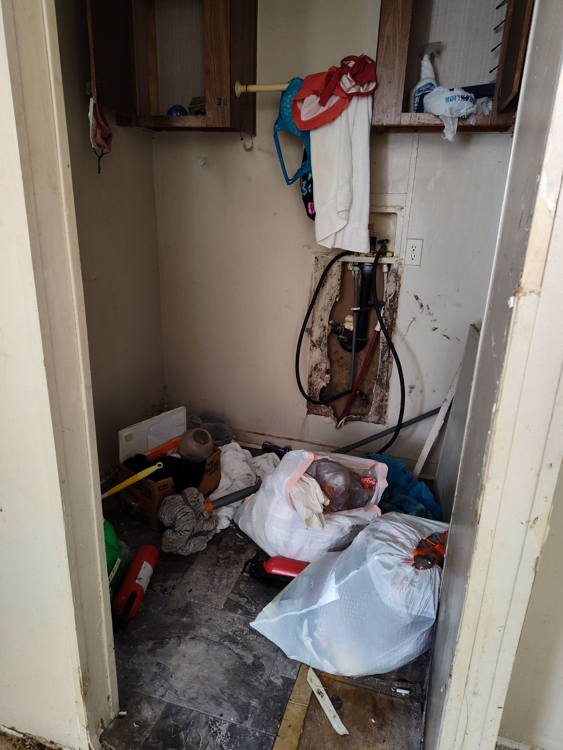 A room with a lot of trash on the floor and a hole in the wall.