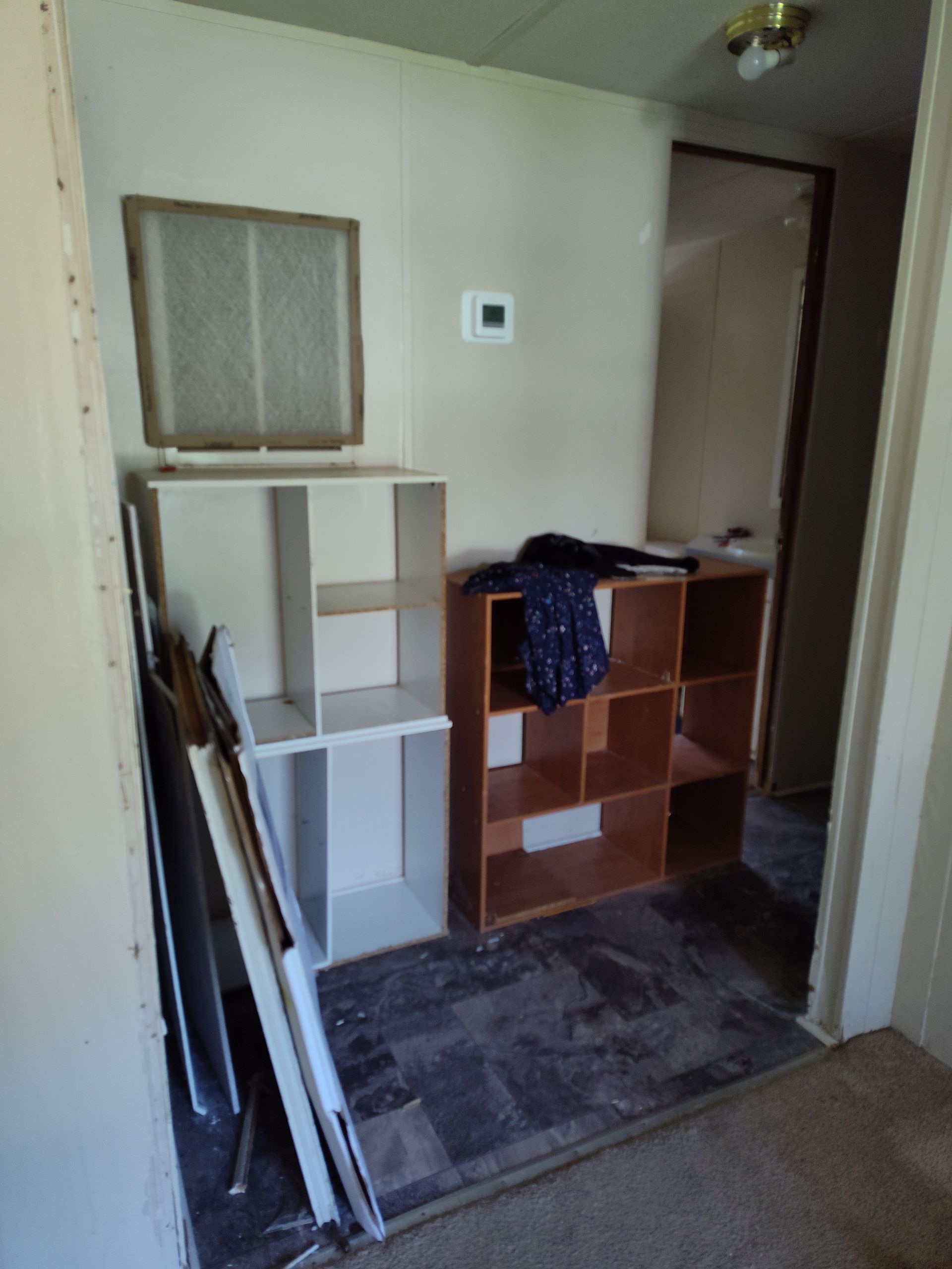A hallway with shelves and a thermostat on the wall
