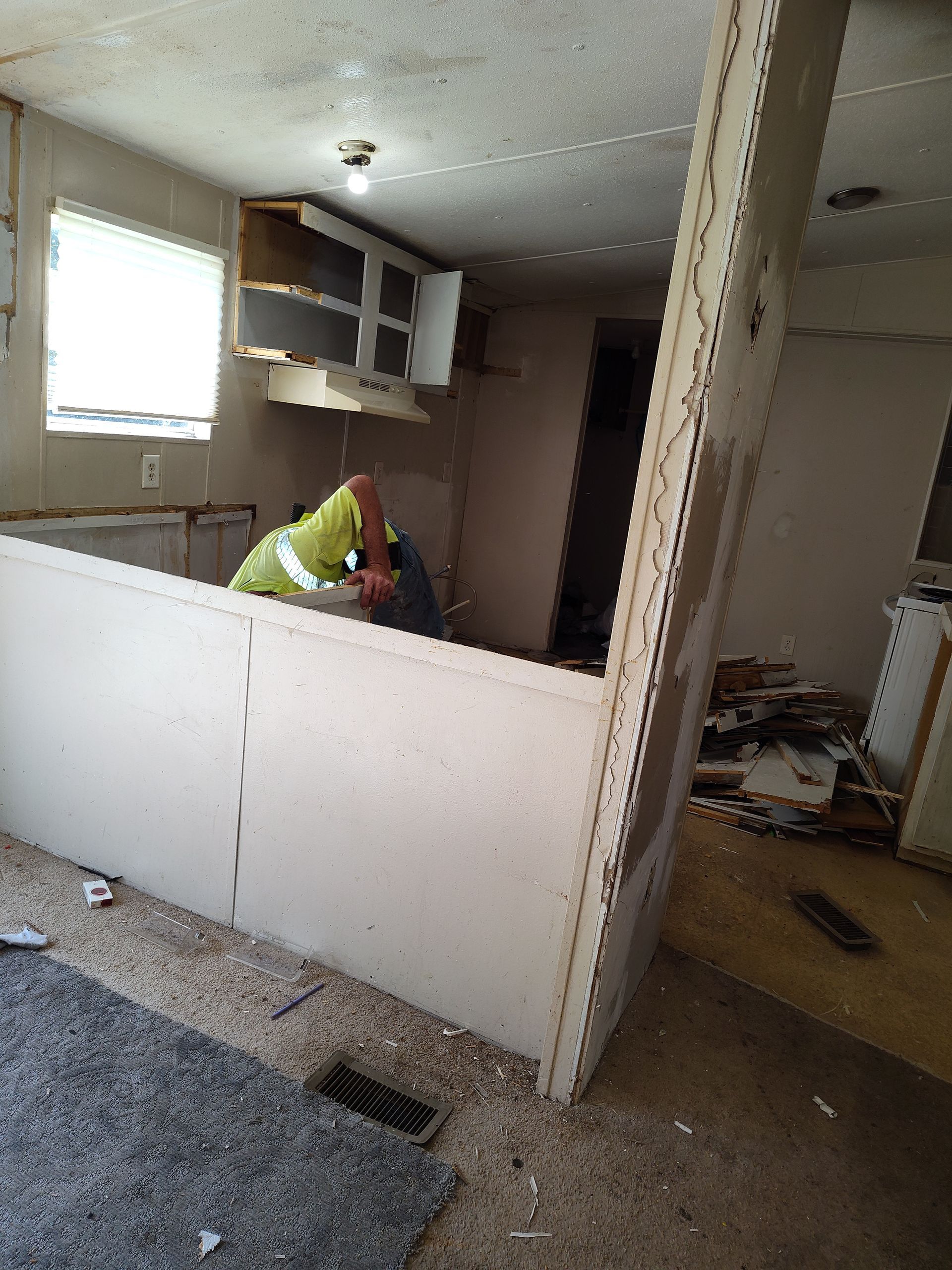 A man is working on a wall in a kitchen.