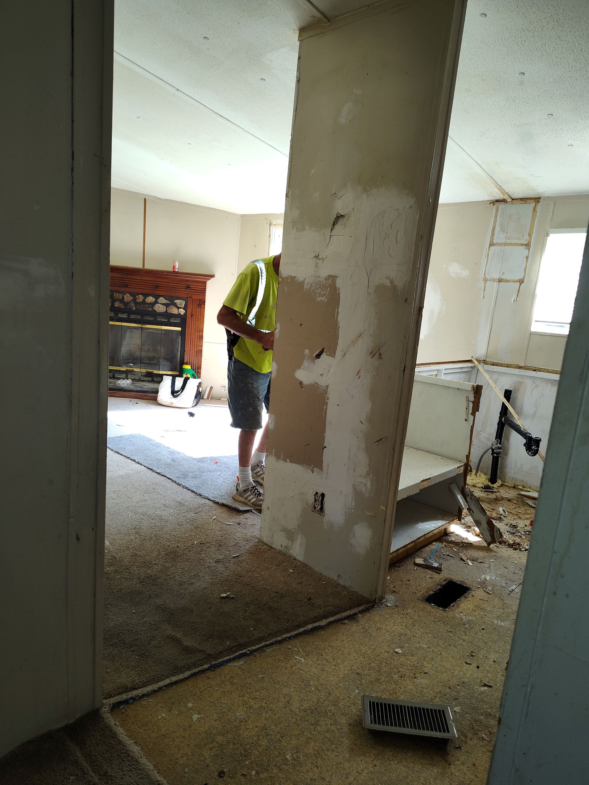 A man in a yellow shirt is standing in a living room.