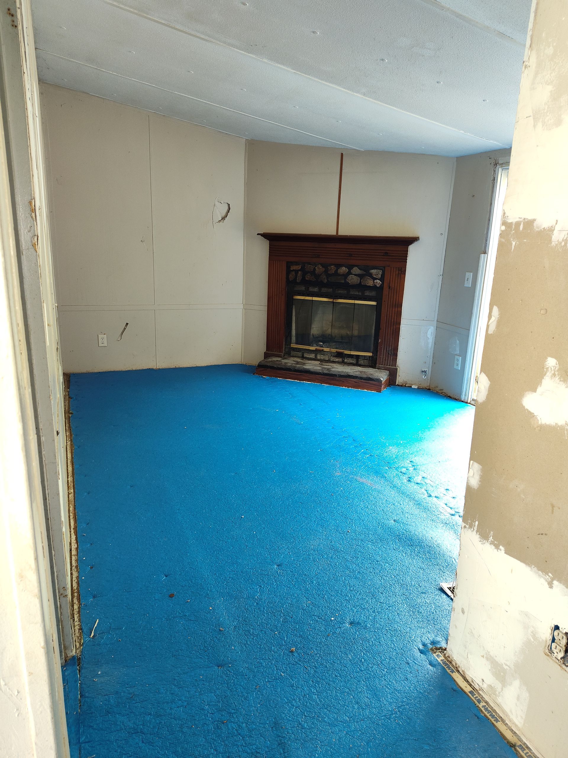 An empty room with a fireplace and blue carpet
