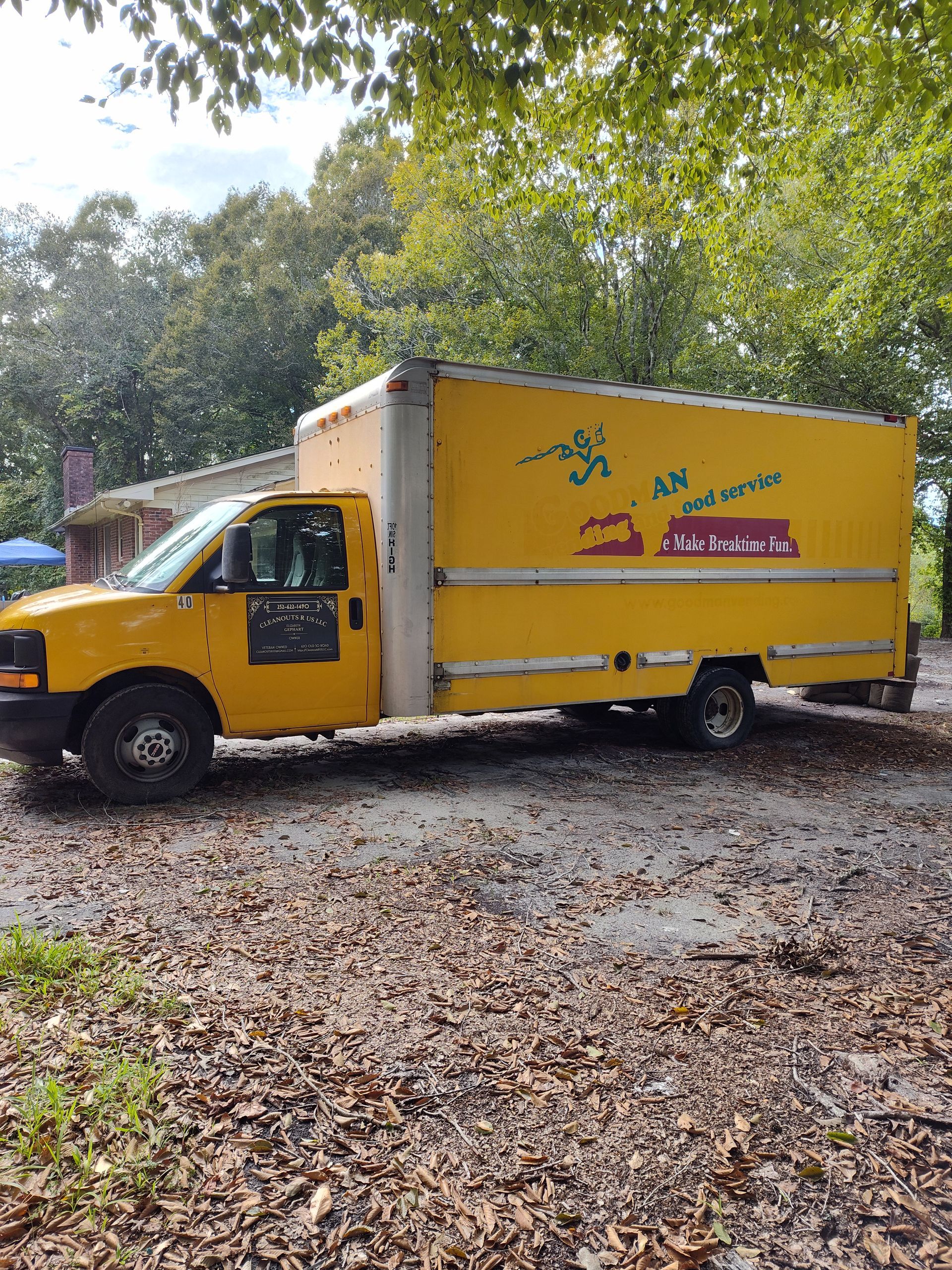 A yellow moving truck is parked in a dirt lot.